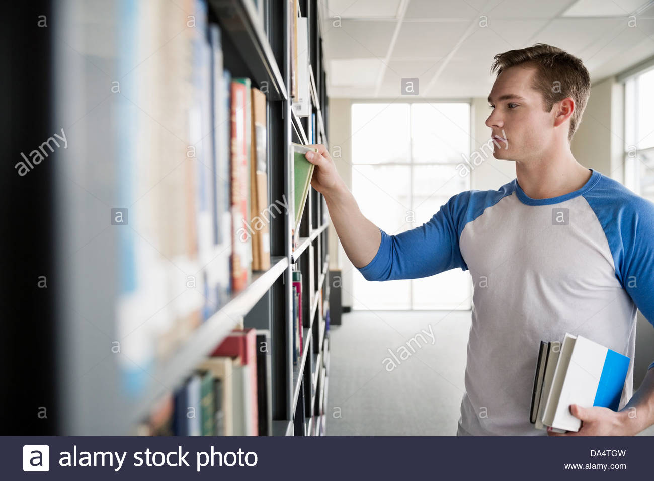 Männlichen Studenten, die Auswahl der Bücher in der Universitätsbibliothek Stockfoto