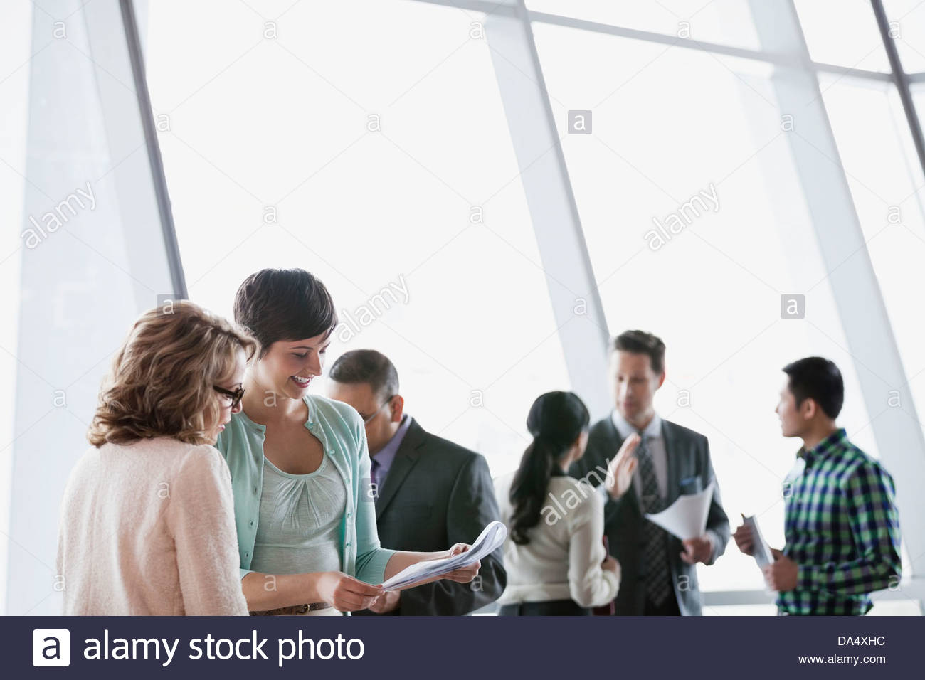 Geschäftsfrau Blick auf Dokument mit Kollegen im Bürogebäude Stockfoto