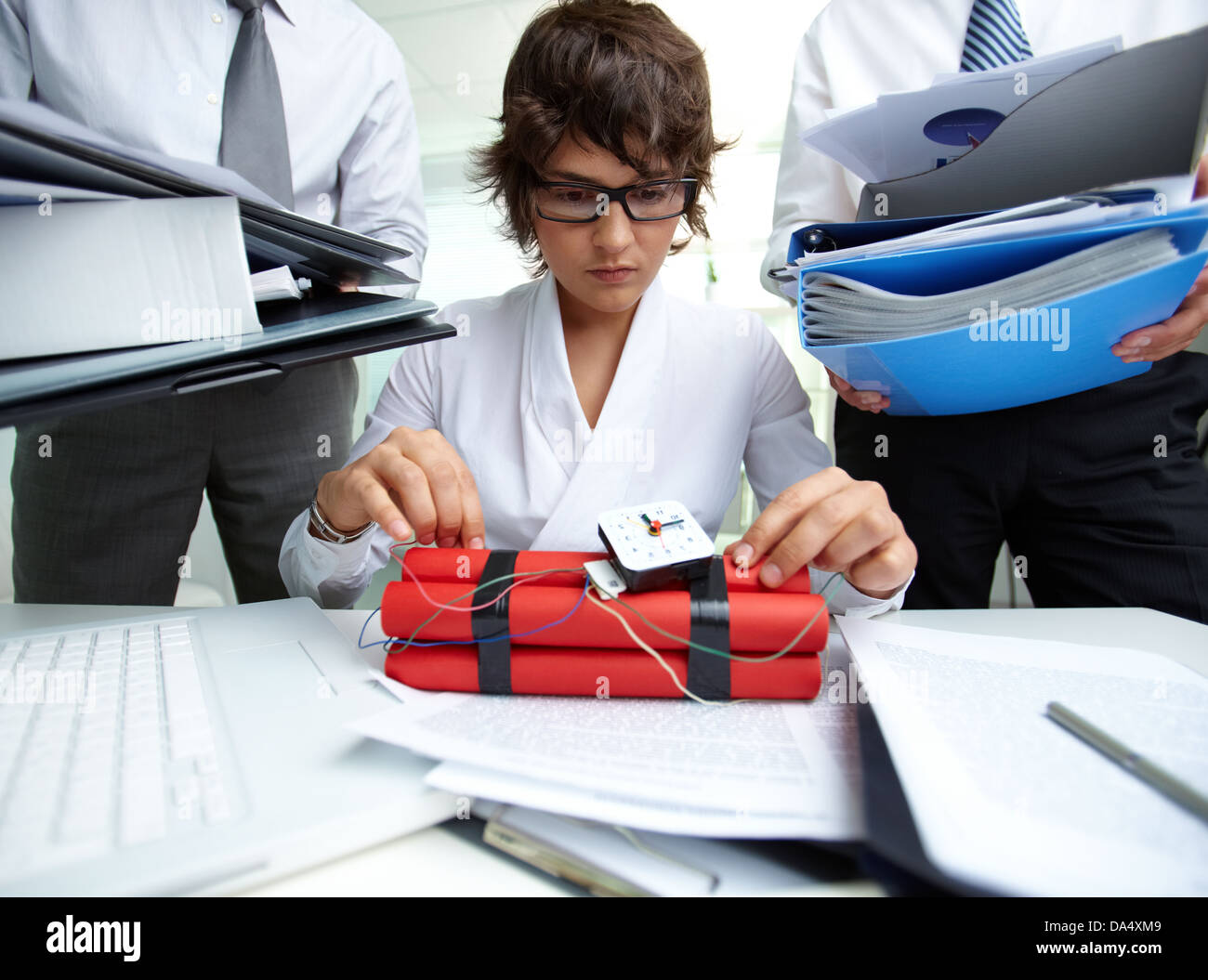 Ernsthafte Sekretär mit Dynamit, umgeben von großen Haufen von Papieren, die von Männern besetzt Stockfoto