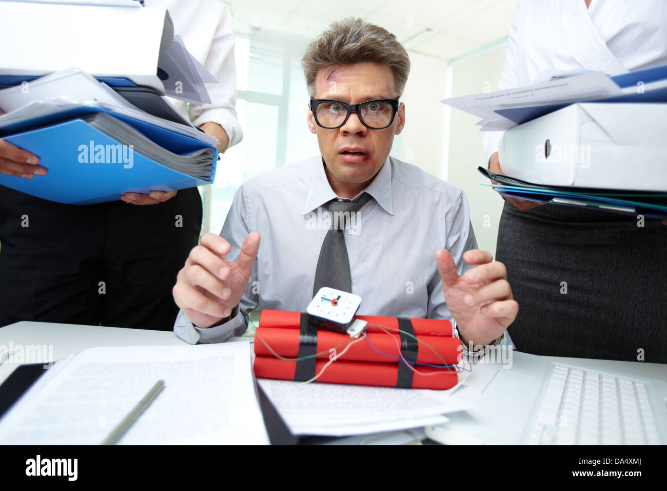 Erschrocken Buchhalter mit Dynamit, umgeben von großen Haufen von Papieren Stockfoto