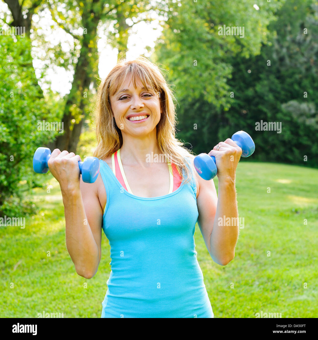 Porträt von weiblichen Fitness-Instruktor Training mit kleinen Gewichten im grünen park Stockfoto