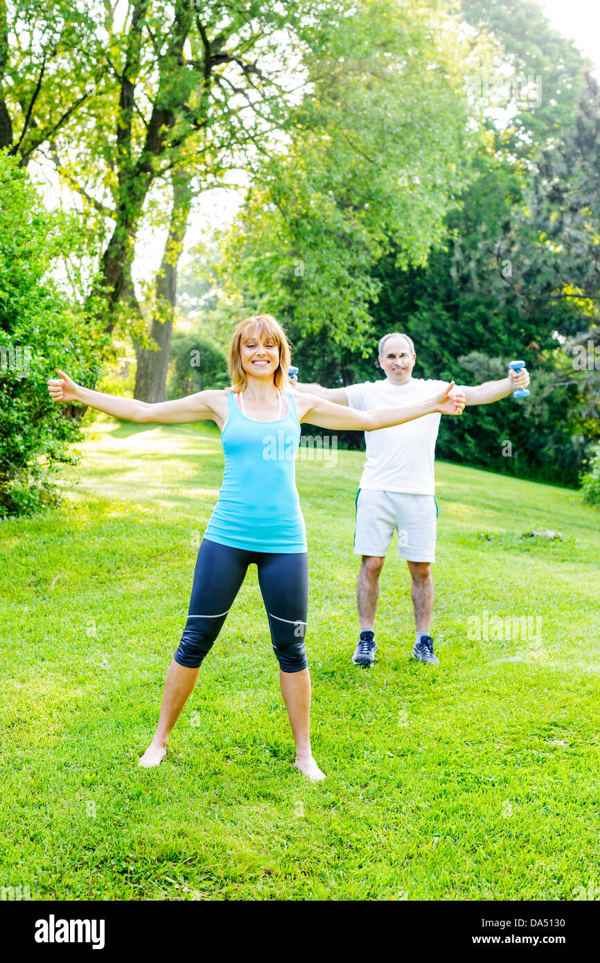 Frauen Fitness-Instruktor Training mit mittleren Alter Mann draußen im grünen park Stockfoto