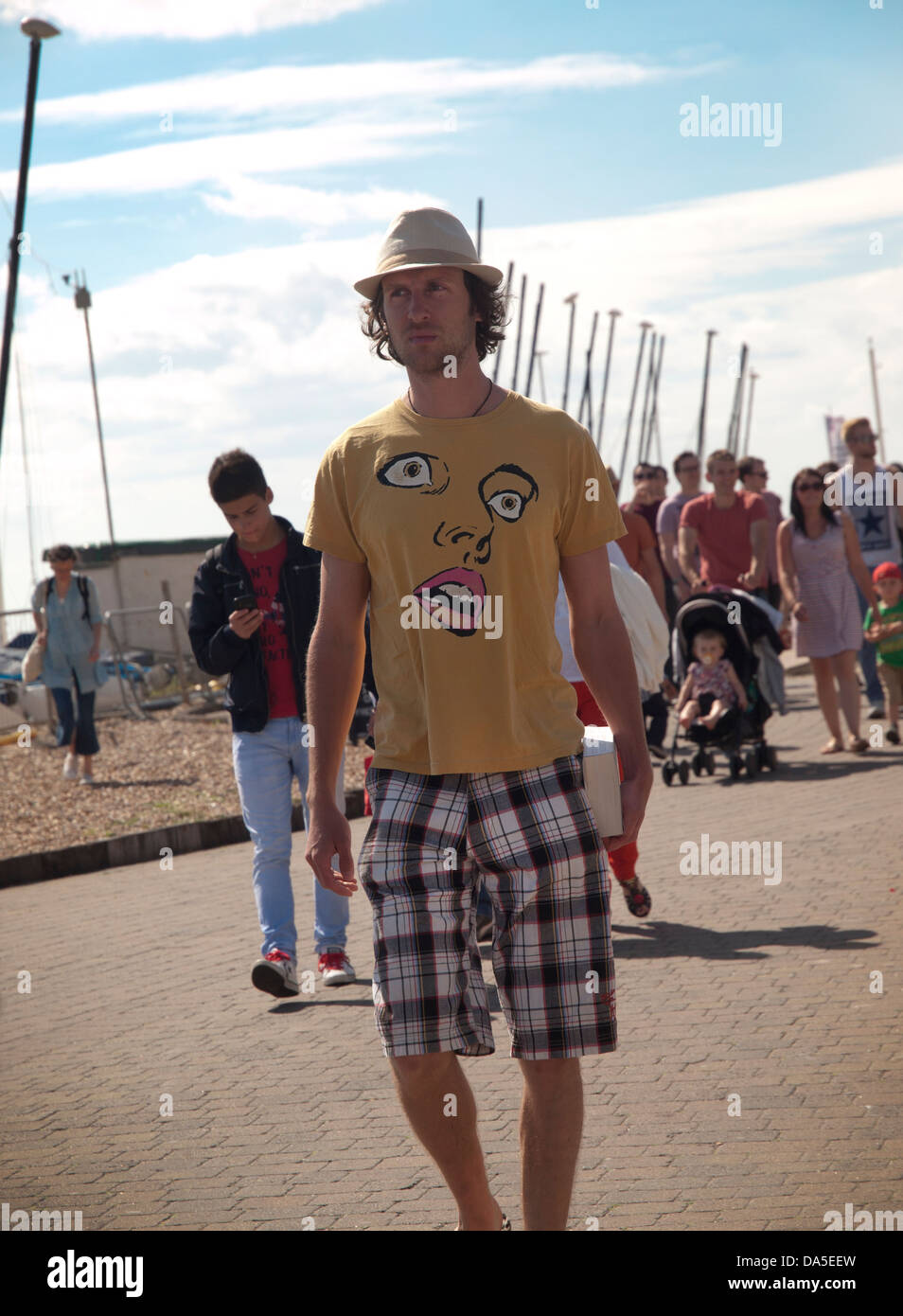 Ein Mann geht entlang der Strandpromenade in einem interessanten t-shirt Stockfoto
