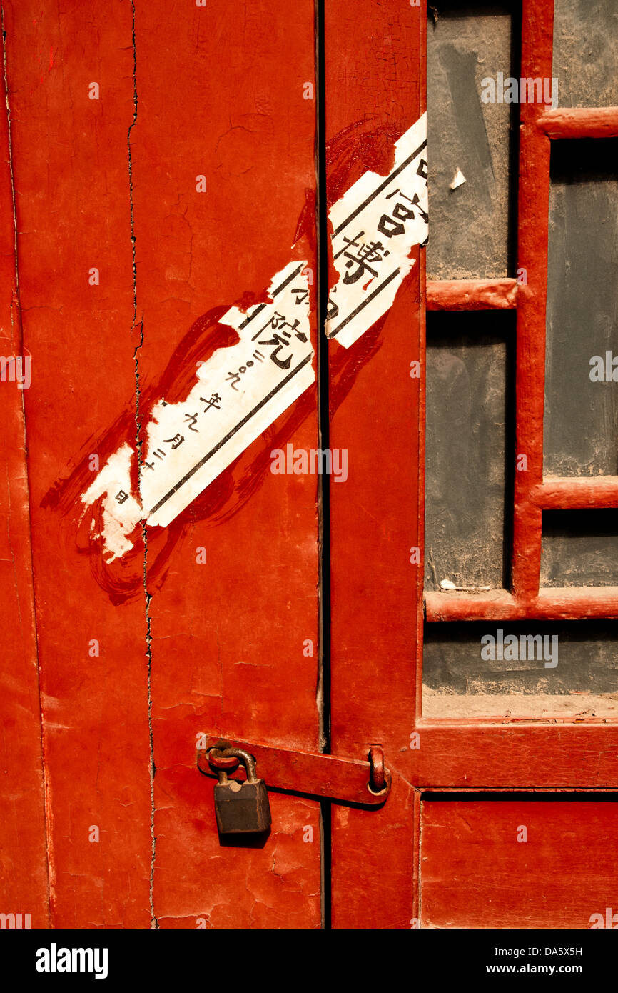 Blick auf eine rote Vorhängeschloss Tür mit verblassten chinesische Schrift beschnitten Stockfoto