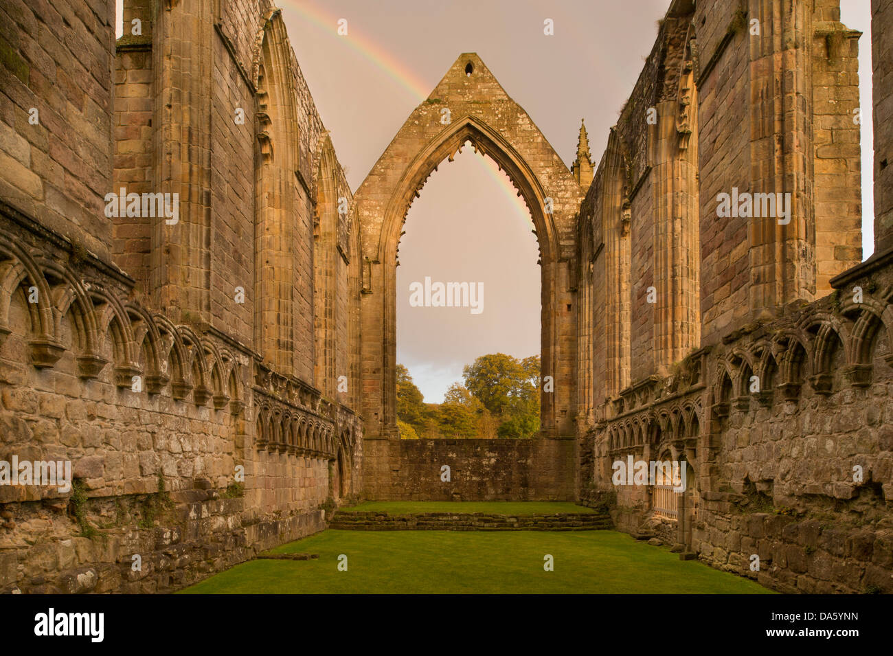 Blick auf die sonnendurchflutete, alten, malerischen monastischen Ruinen von Bolton Abbey mit Regenbogen in dunklen Himmel über ostchor Fenster - Yorkshire Dales, England, UK. Stockfoto