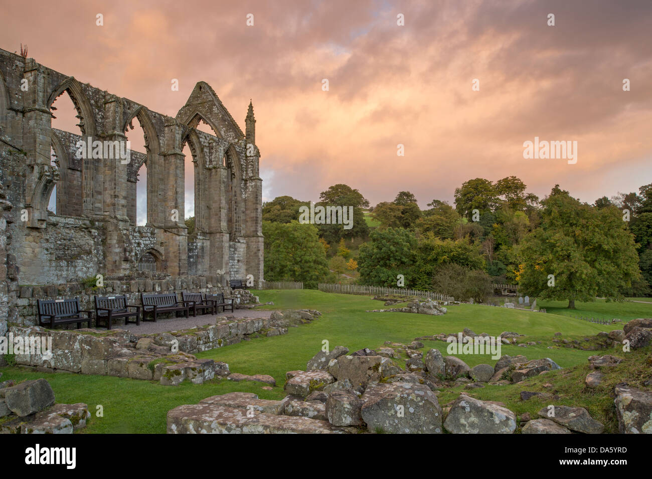 Blick auf die sonnendurchflutete, alten, malerischen monastischen Ruinen von Bolton Abbey in der malerischen Landschaft gegen dramatischen Sonnenuntergang Himmel - Yorkshire Dales, England, UK. Stockfoto