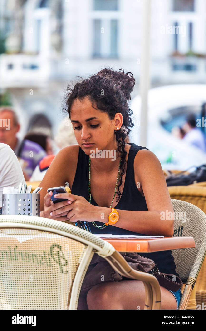 Eine attraktive junge Frau nutzt ihr iPhone sitzen in einem Straßencafé am Altstädter Ring, Prag Stockfoto