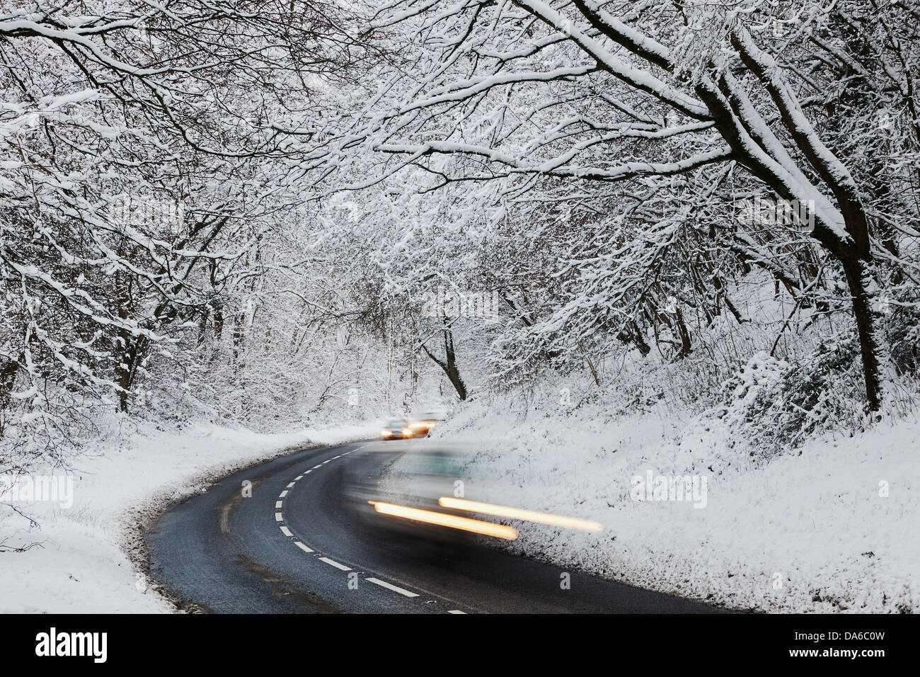 Eine winterliche Ansicht einer Straße, die durch verschneiten Wald läuft, in Burrington Combe, in der Nähe von Langford, Somerset, Großbritannien. Stockfoto