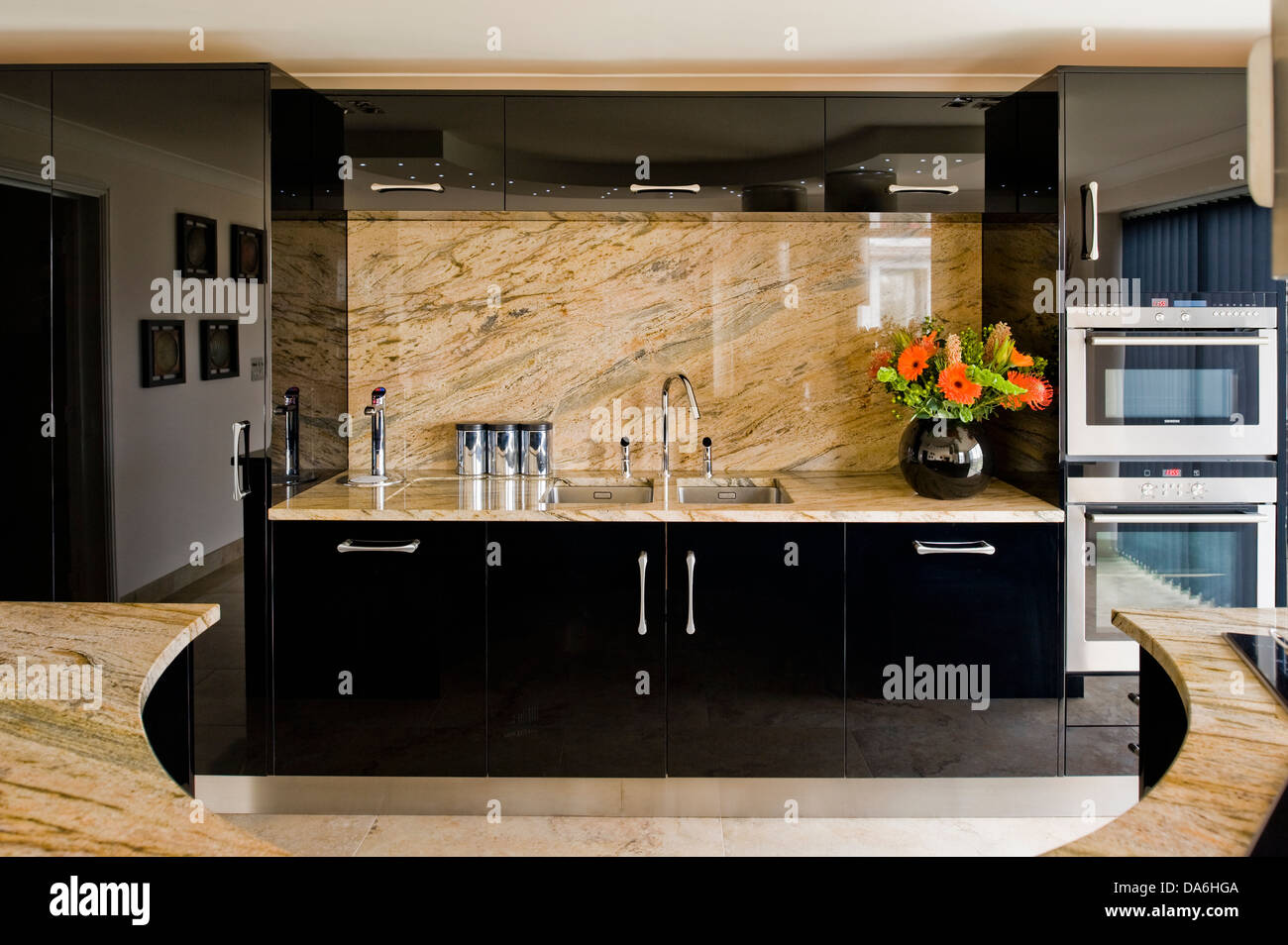 Blasse Marmor Splash-Rücken und Arbeitsplatte auf schwarzen ausgestattete Einheit in modernen Küche mit gebogenen Mittelinsel Einheit Stockfoto