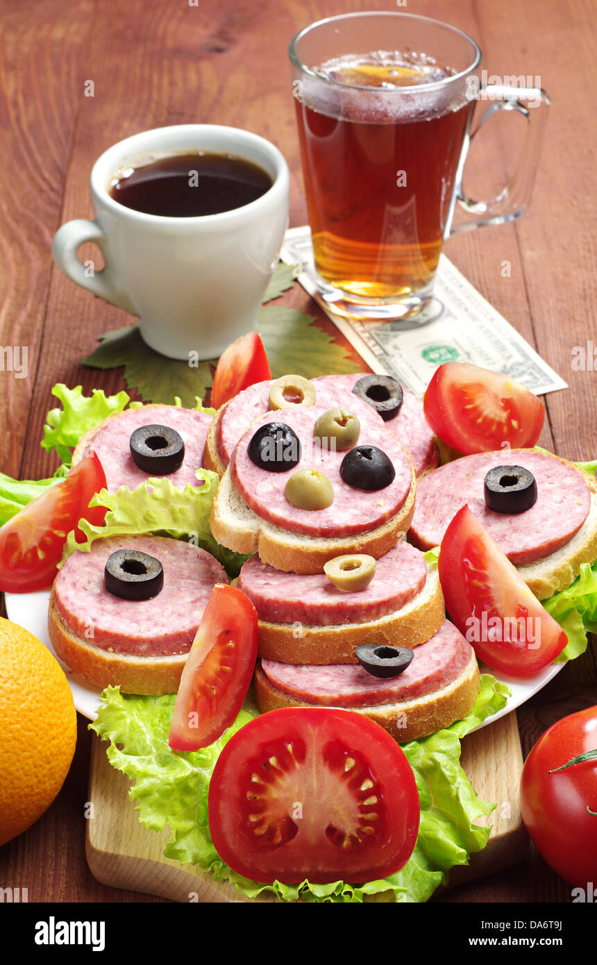 Brötchen mit Wurst, Kaffee, Tee und einen Dollar auf einem Holztisch Stockfoto