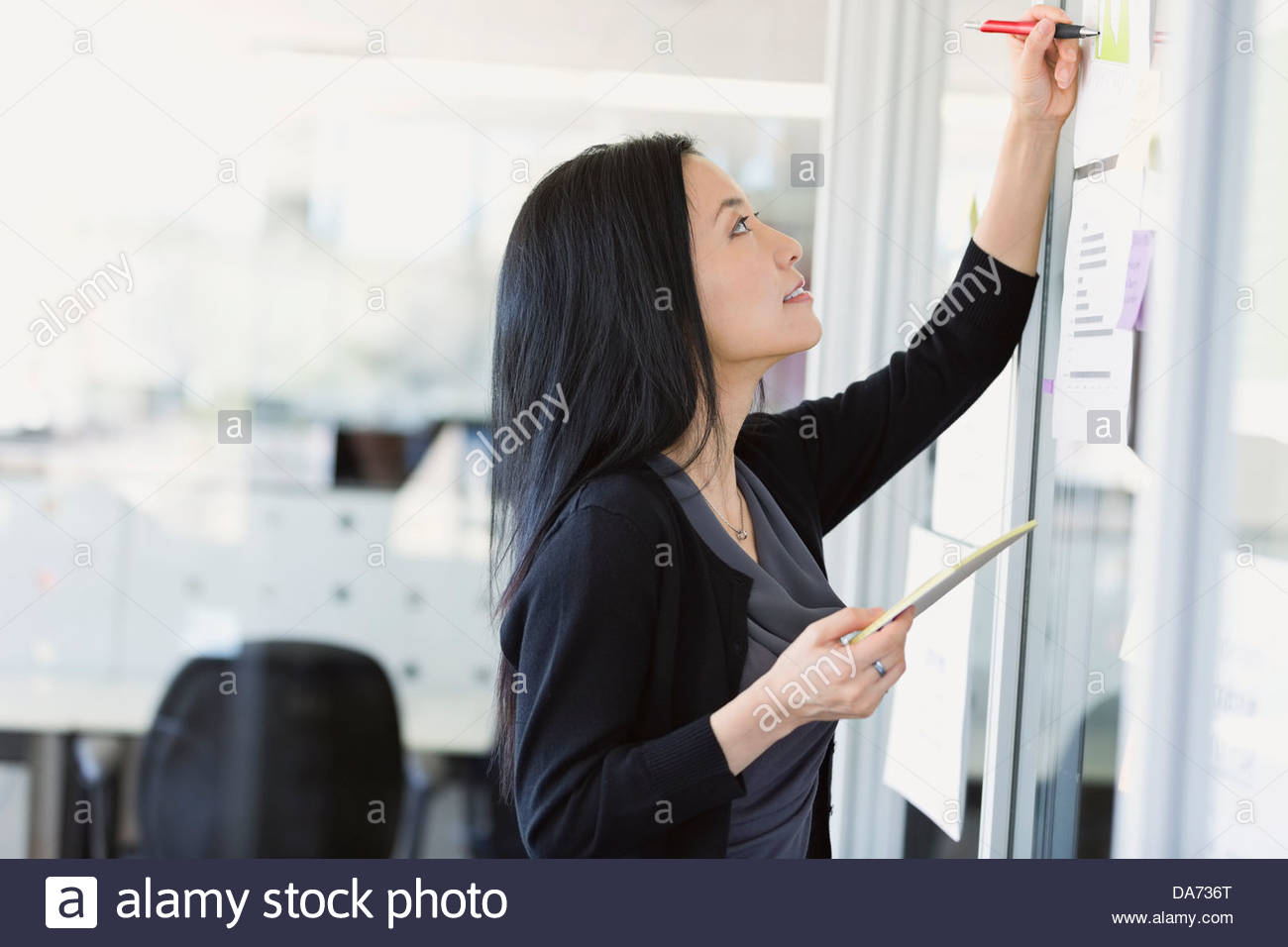 Geschäftsfrau, die Schreiben von Notizen auf Projekt Visuals im Büro Stockfoto