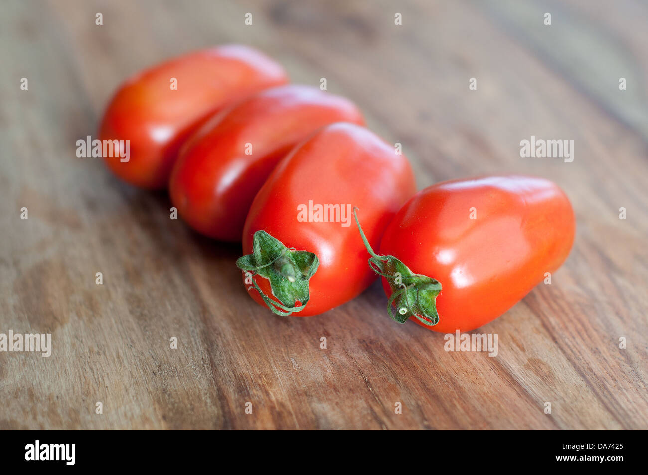 Vier Roma-Tomaten auf hölzernen Hintergrund Stockfoto