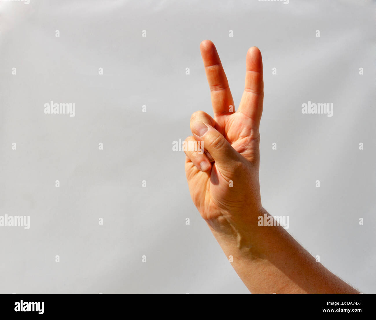 Mann Hand zeigt die Geste Sieg Zeichen Closeup. Hintergrund ist nicht abgeschnitten, es ist wirklich weiß. Stockfoto