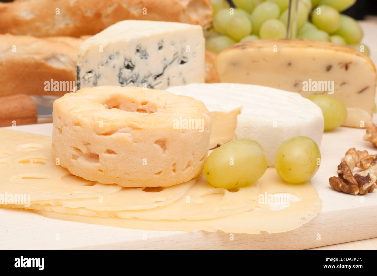 Verschiedene Arten von Käse, Trauben und Walnüssen auf Schneidbrett aus Holz Stockfoto