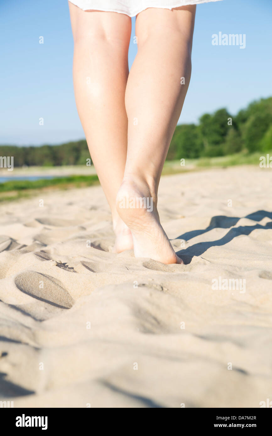 Junge Frau Beine Schritt am warmen Sandstrand Stockfoto