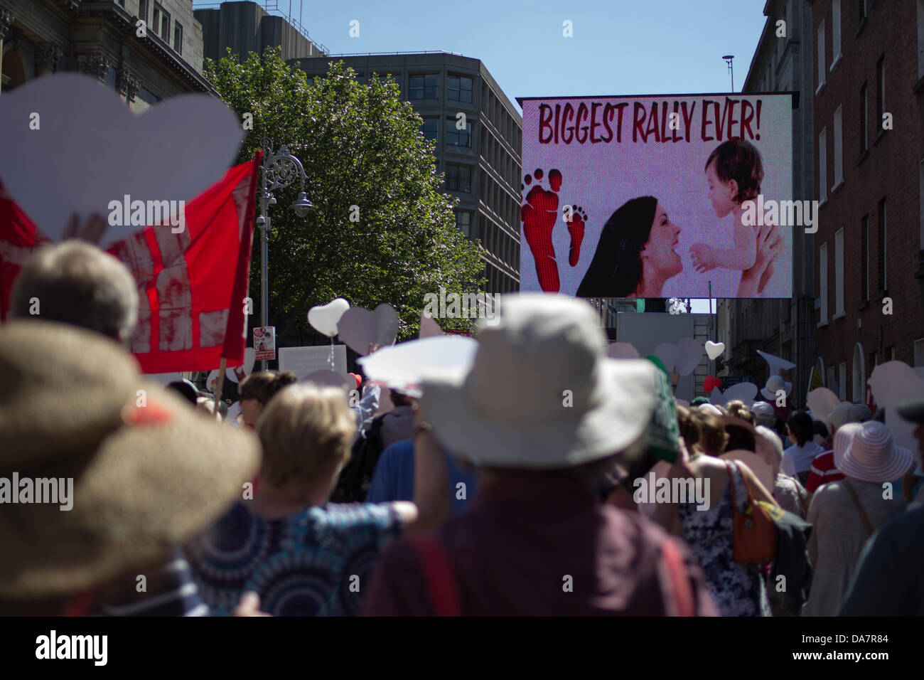 Dublin, Irland, 6. Juli 2013. Menschenmassen von Abtreibungsgegnern marschieren durch die Innenstadt während einer pro-life-Kundgebung gegen die Abtreibungsgesetze, die im Oireachtas diskutiert werden. Ein großer Bildschirm zeigt eine Frau und ein Baby mit dem Slogan „Größte Kundgebung aller Zeiten!“ während die Demonstranten Banner und herzförmige Plakate halten. Die öffentliche Demonstration veranschaulicht Streitigkeiten über reproduktive Rechte, Frauengesundheit, körperliche Autonomie, den Einfluss der katholischen Kirche, die traditionelle irische Gesellschaft, religiösen Konservatismus, Kulturkämpfe, Meinungsfreiheit, öffentliche Ordnung und die Geschichte des achten Verfassungszusatzes. Stockfoto