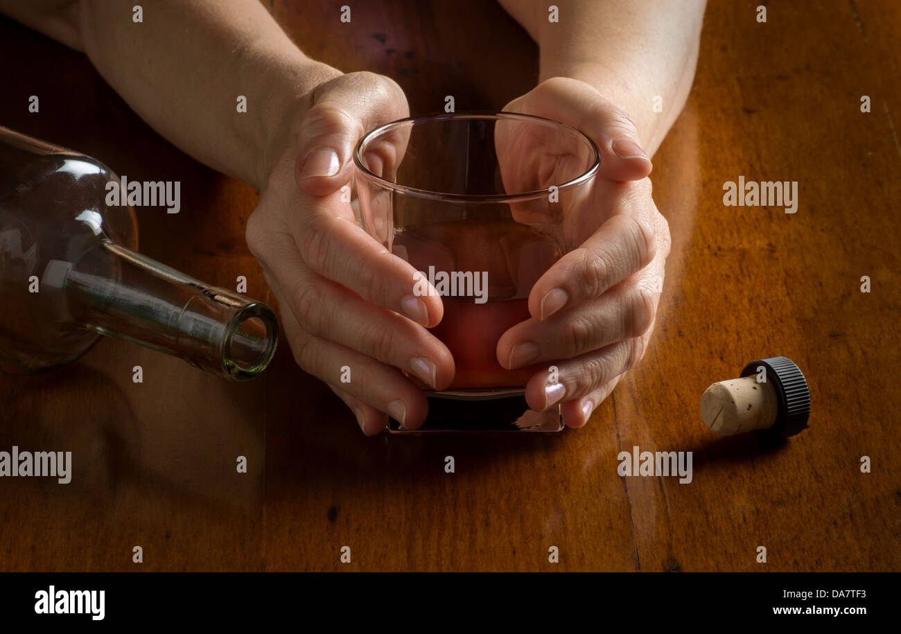 Konzept-Foto-Closeup für Alkoholismus Krankheit zeigt Hände Whiskeyglas und leere Flasche Stockfoto