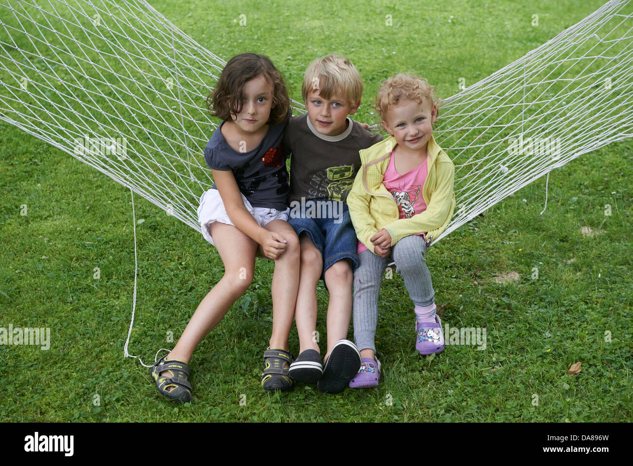 Gruppe von Kinder Jungen und Mädchen sitzen auf einem Garten Hängematte Stockfoto