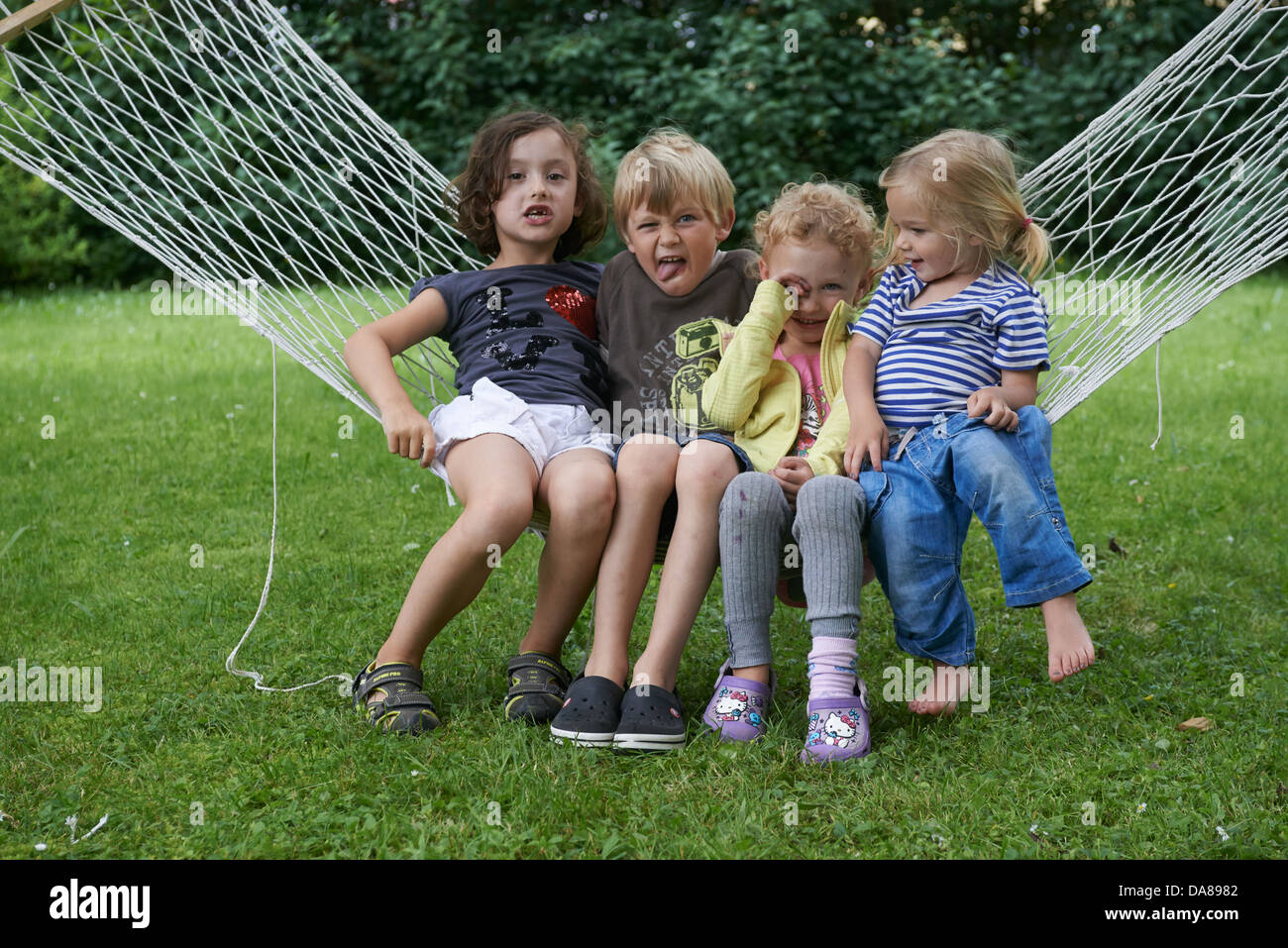 Gruppe von Kinder Jungen und Mädchen sitzen auf einem Garten Hängematte Stockfoto