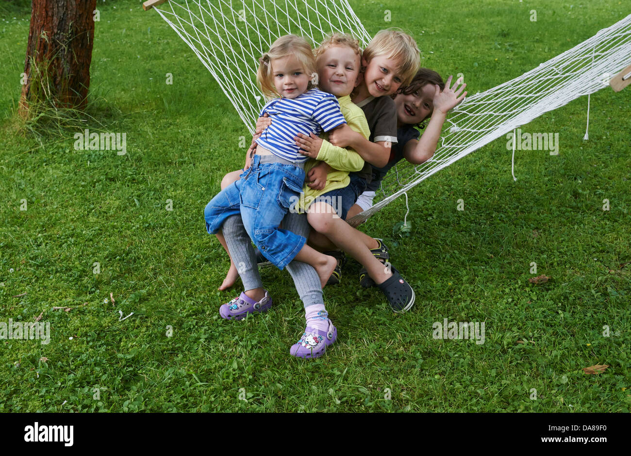 Gruppe von Kinder Jungen und Mädchen sitzen auf einem Garten Hängematte Stockfoto