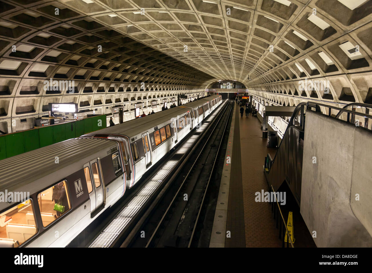 U-Bahn-Zug durch eine unterirdische u-Bahnstation in Washington D.C.  Pendler warten auf der Plattform. Stockfoto