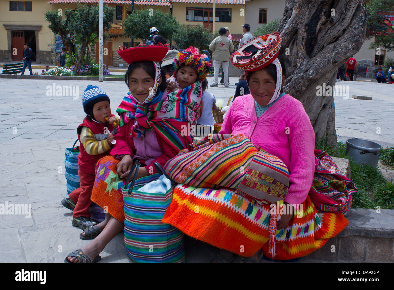 Portrait von lächelnden Frauen und Kinder in bunten Trachten im Park sitzen, Cusco, Sacred Valley, Peru. Stockfoto