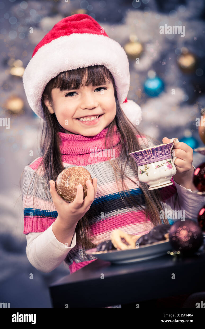 kleines Mädchen mit Santa Cap am Weihnachtsbaum Stockfoto