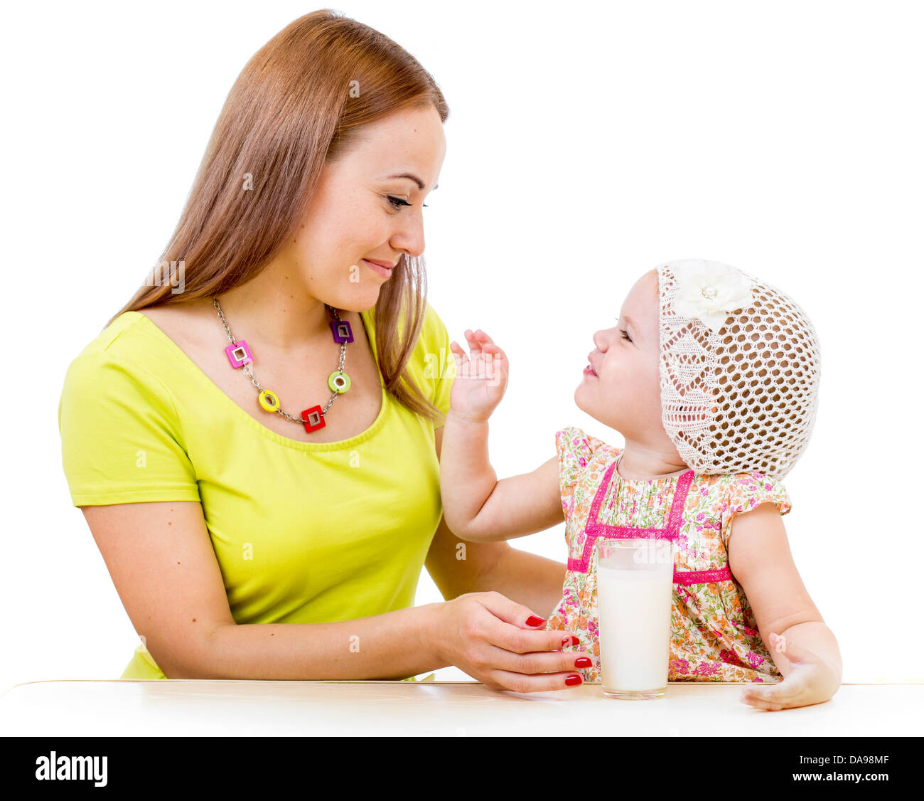 Mutter, Milchglas, kleines Mädchen sitzt am Tisch, die isoliert auf weiss Stockfoto