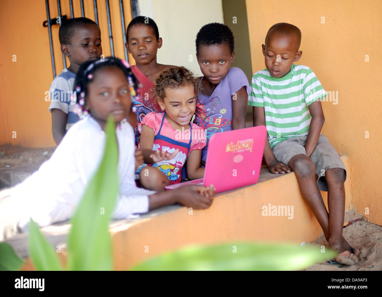 Kinder sitzen um eine pädagogische Computer auf Inhaca Island in Mosambik, 23. Februar 2013. Foto: Britta Pedersen Stockfoto