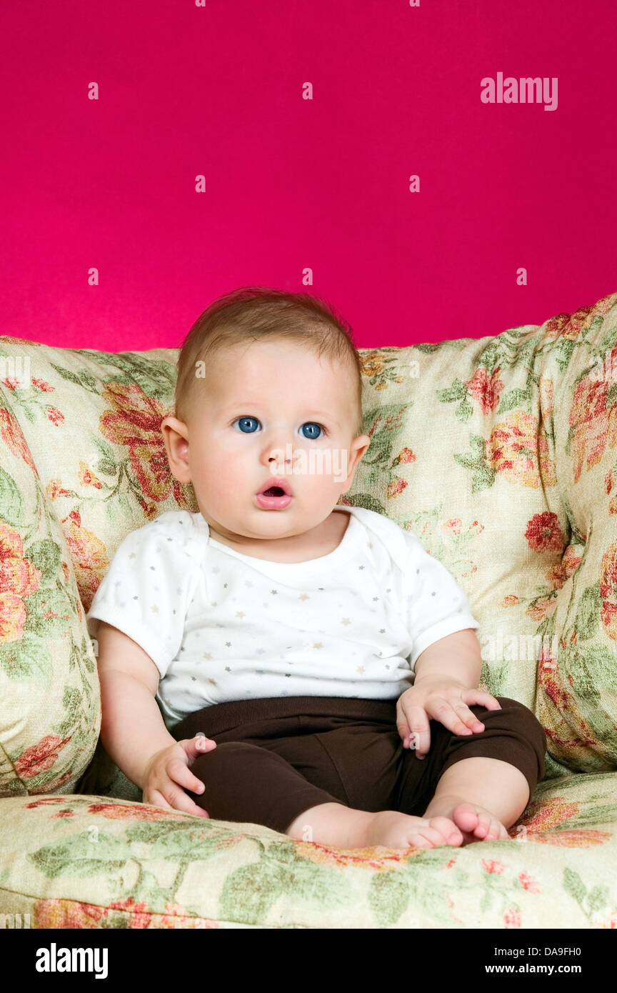 Baby Boy auf dem Stuhl sitzt und auf der Suche Stockfoto