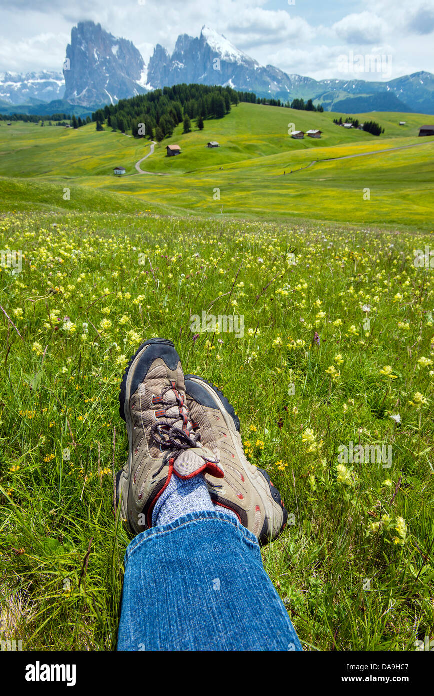 Gekreuzten Beinen ein Wanderer am Alpe di Siusi oder Seiser Alm mit Langkofel Berg hinter, Dolomiten, Alto Adige Südtirol, Italien Stockfoto