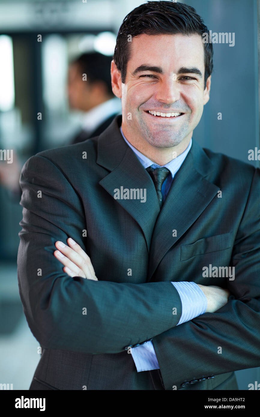 fröhliche gut aussehend Geschäftsmann mit im Büro verschränkten Armen Stockfoto