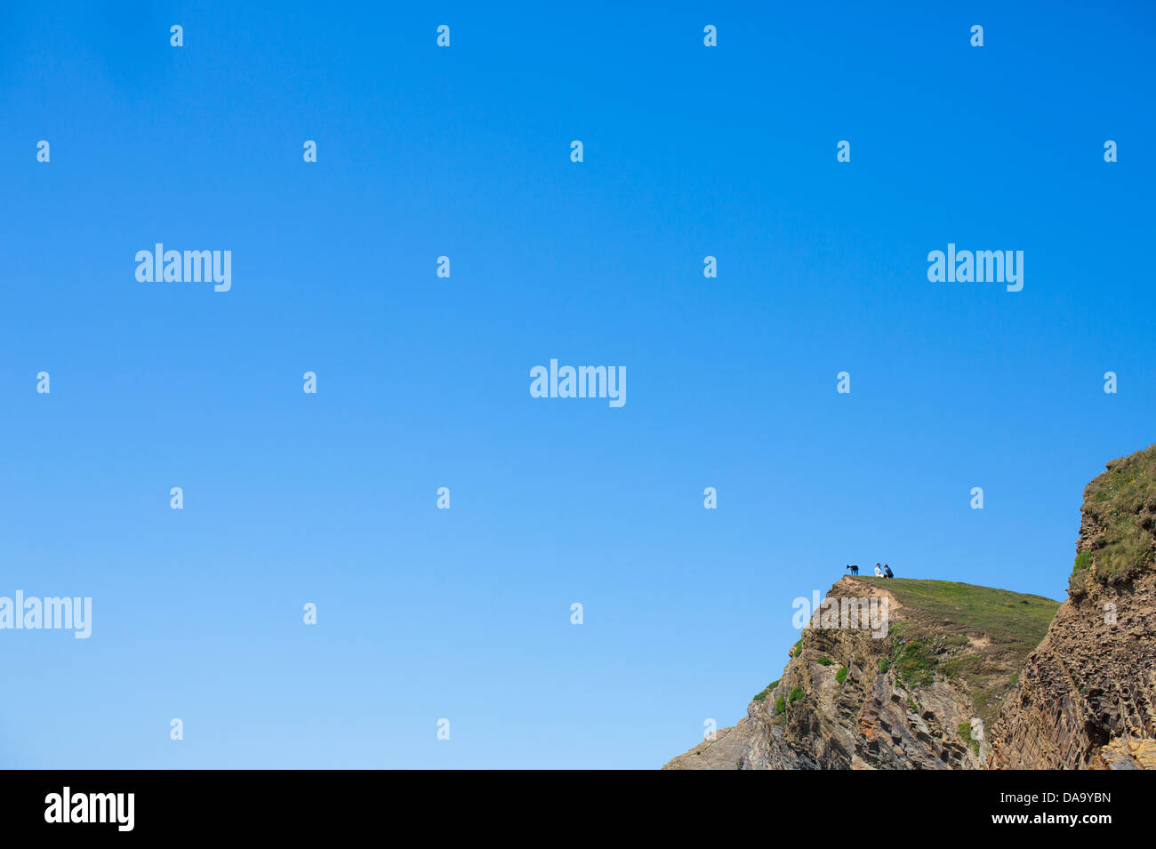 Menschen und ihr Hund sitzen auf einer Klippe über der Bucht von Sandymouth, North Devon, England Stockfoto