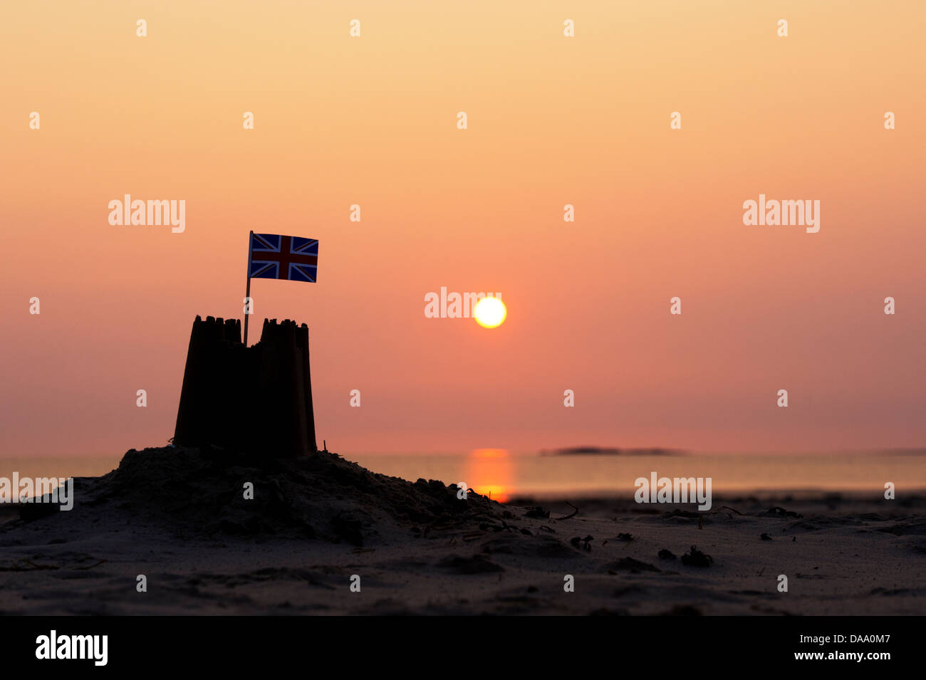 Sandburg mit Fahne Silhouette bei Sonnenaufgang am Strand. Northumberland, England Stockfoto