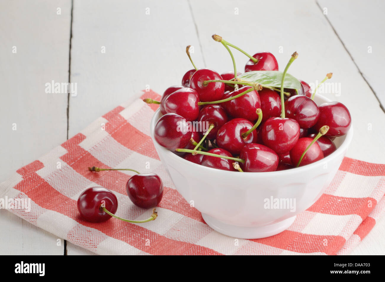 Keramikschale weiß Bio Kirschen auf weißem Tisch Stockfoto