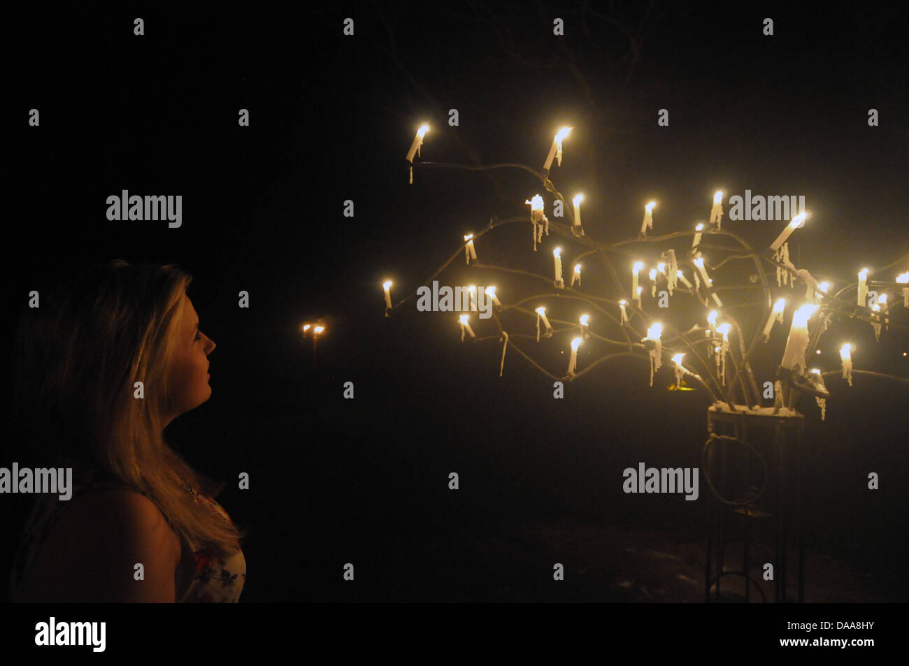 Mädchen mit vielen Kerzen Tropfen Wachs in dunklen geheimnisvollen Kandelaber Stockfoto