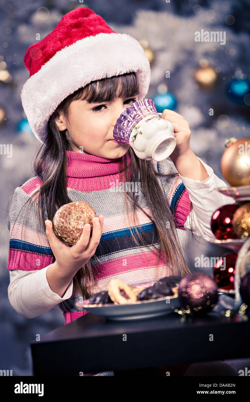 kleines Mädchen mit Santa Cap am Weihnachtsbaum Stockfoto