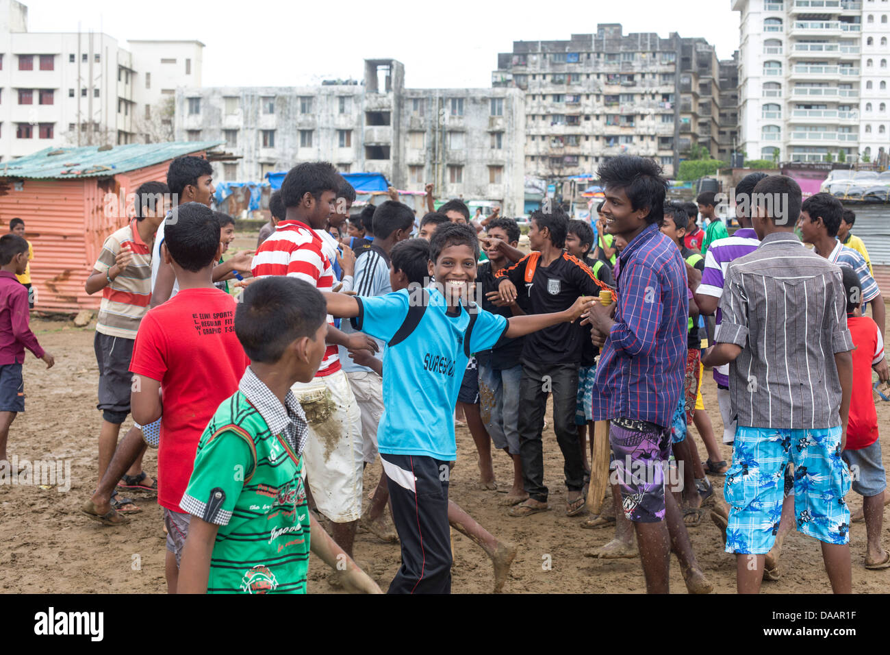 Mumbai-Fischer und ihre Kinder spielen Cricket während der Monsun-Wetter sie hält Angeln auf Brachland hinter Slums. Stockfoto