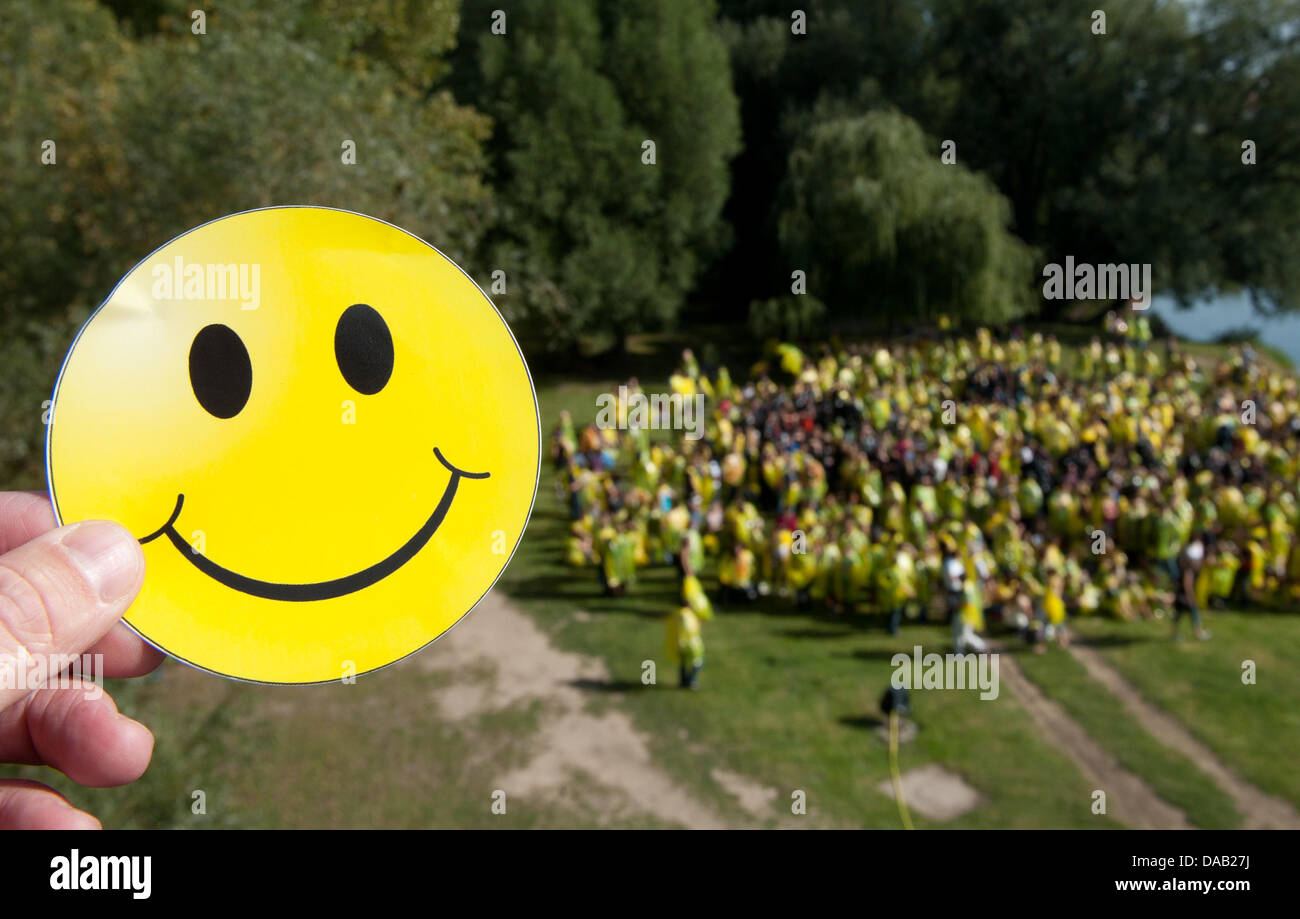 (ABBILDUNG) Eine Abbildung vom 24. September 2011 zeigt einen Smiley-Aufkleber vor zahlreichen Menschen Stand tragen gelbe und schwarze Raincaps auf der Jahn-Insel und bilden einen Smiley in Regensburg, Deutschland. Organisatoren wollten den Rekord für den größten Smiley, gemacht von Menschen mit der Aktion "Regensburg lächelt" mit fast 3000 Teilnehmer zu brechen. Leider nur rund die Hälfte Stockfoto