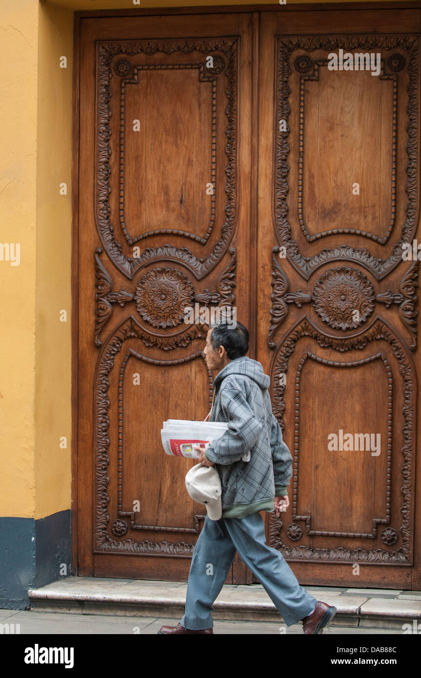 Älteren alten Mann zu Fuß auf Bürgersteig neben kunstvoll geschnitzten Holztüren Holz Tür Straßenbild Innenstadt von Trujillo, Peru. Stockfoto