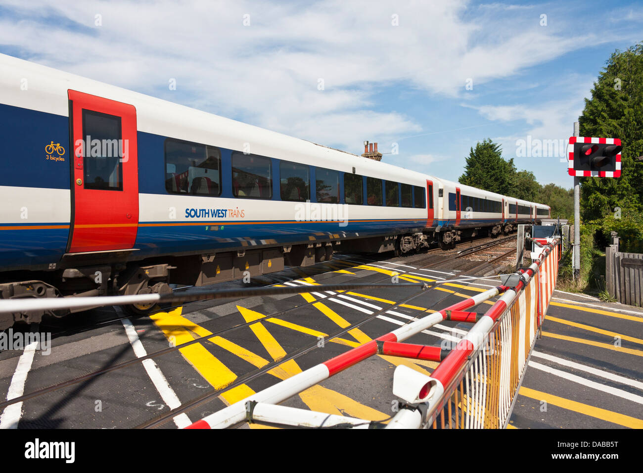 Barrieren sind unten an einen englischen Bahnübergang wie ein Zug im New Forest geht. Brockenhurst, Hampshire, England, GB, UK Stockfoto