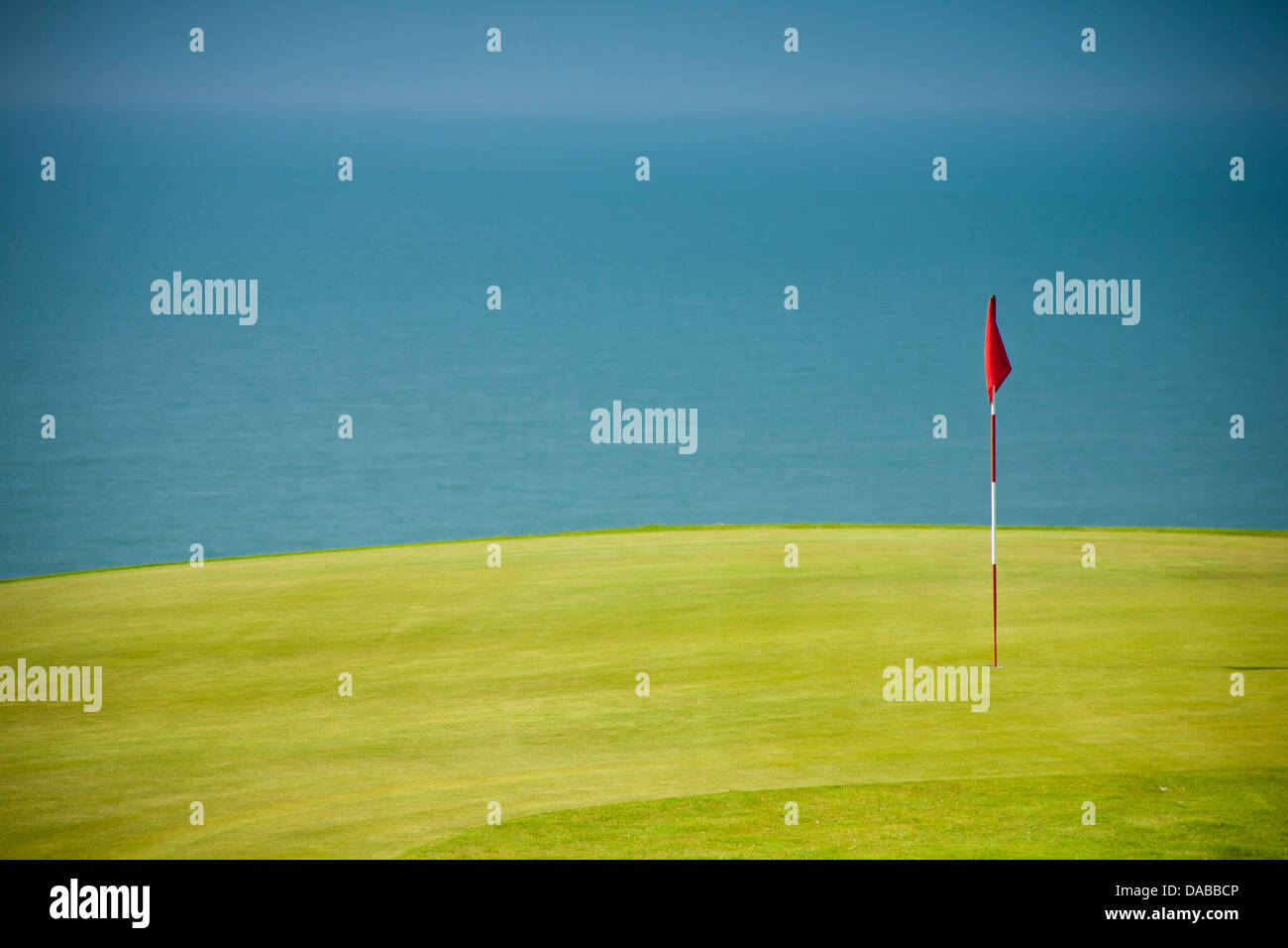 Golfflagge in hellem Grün Grün mit Blau des Meeres im Hintergrund. Stockfoto