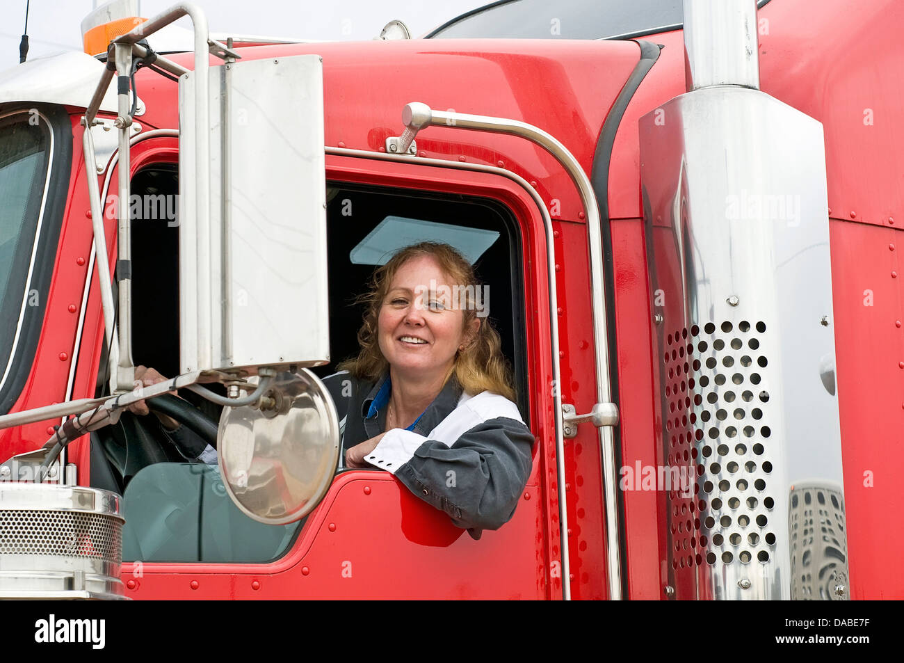 Frau-LKW-Fahrer in der Kabine eines roten semi-LKW Stockfoto