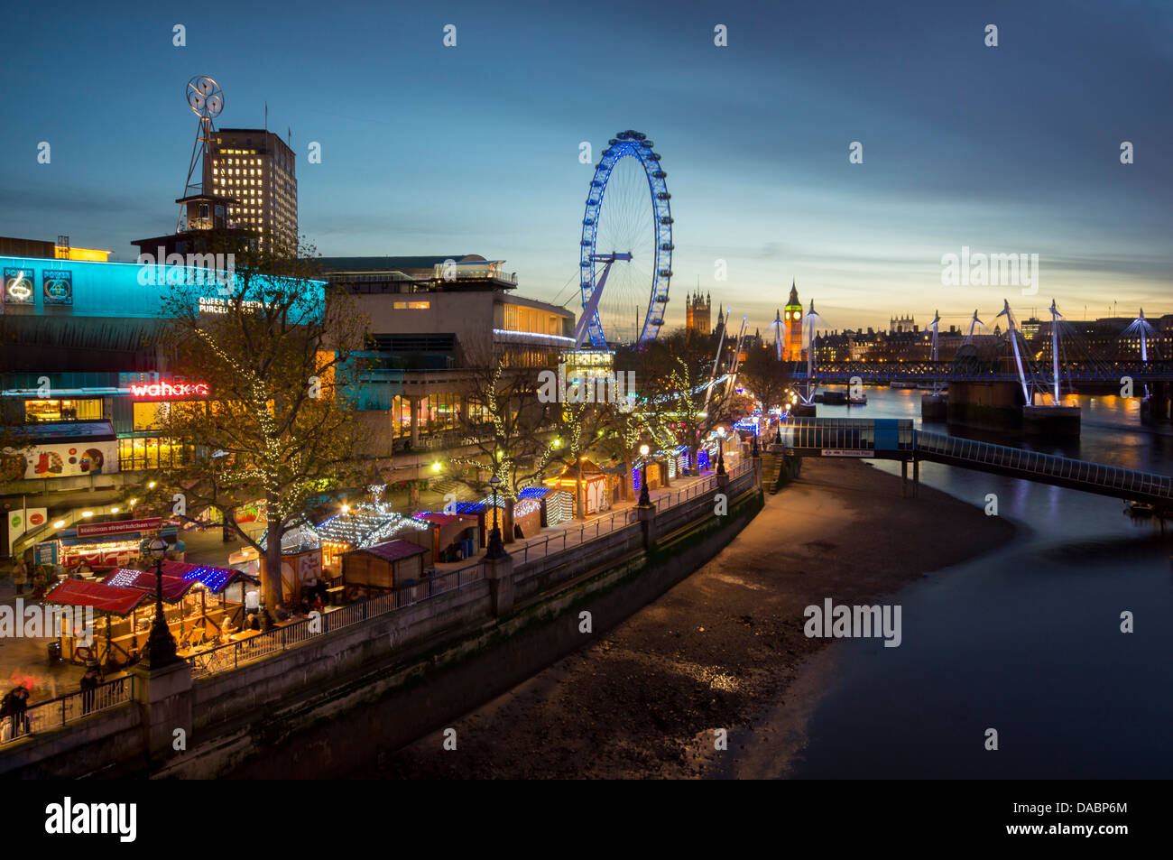 Weihnachtsmarkt ist am Südufer mit Big Ben, Houses of Parliament und London Eye in der Abenddämmerung hinter London, England, UK Stockfoto