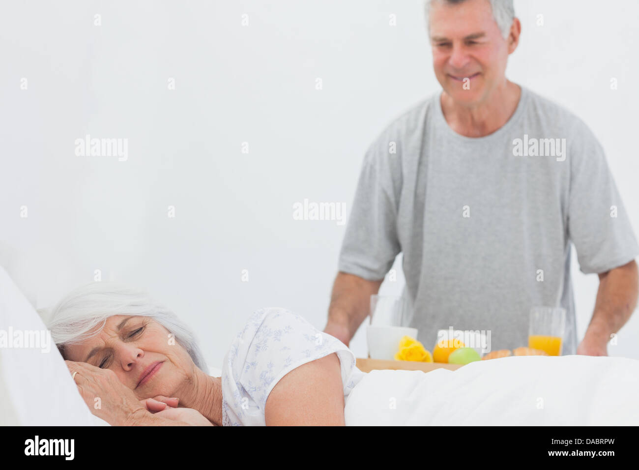 Reifer Mann bringen schlafende Frau Frühstück im Bett Stockfoto