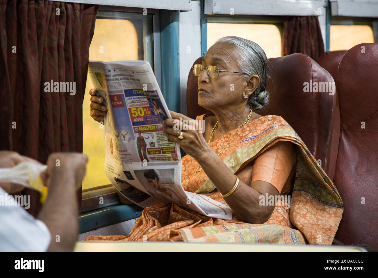 Frau liest eine Zeitung auf einen Zug in Kerala, Indien Stockfoto