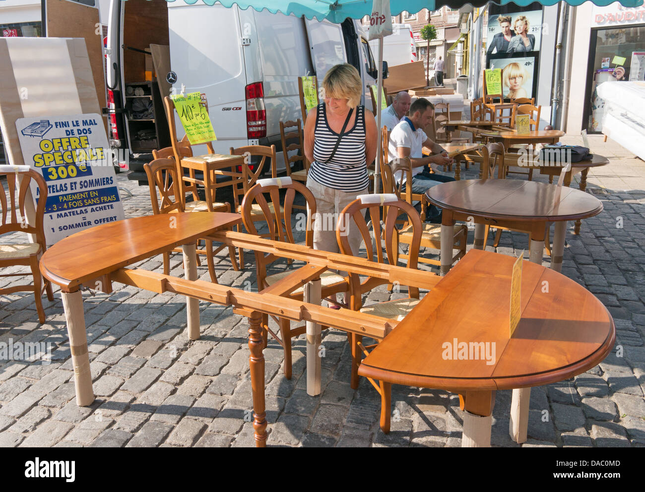 Eine Frau untersucht ein expandierendes Holztisch auf einem Freiluftmarkt in Peronne, Nordfrankreich Stockfoto