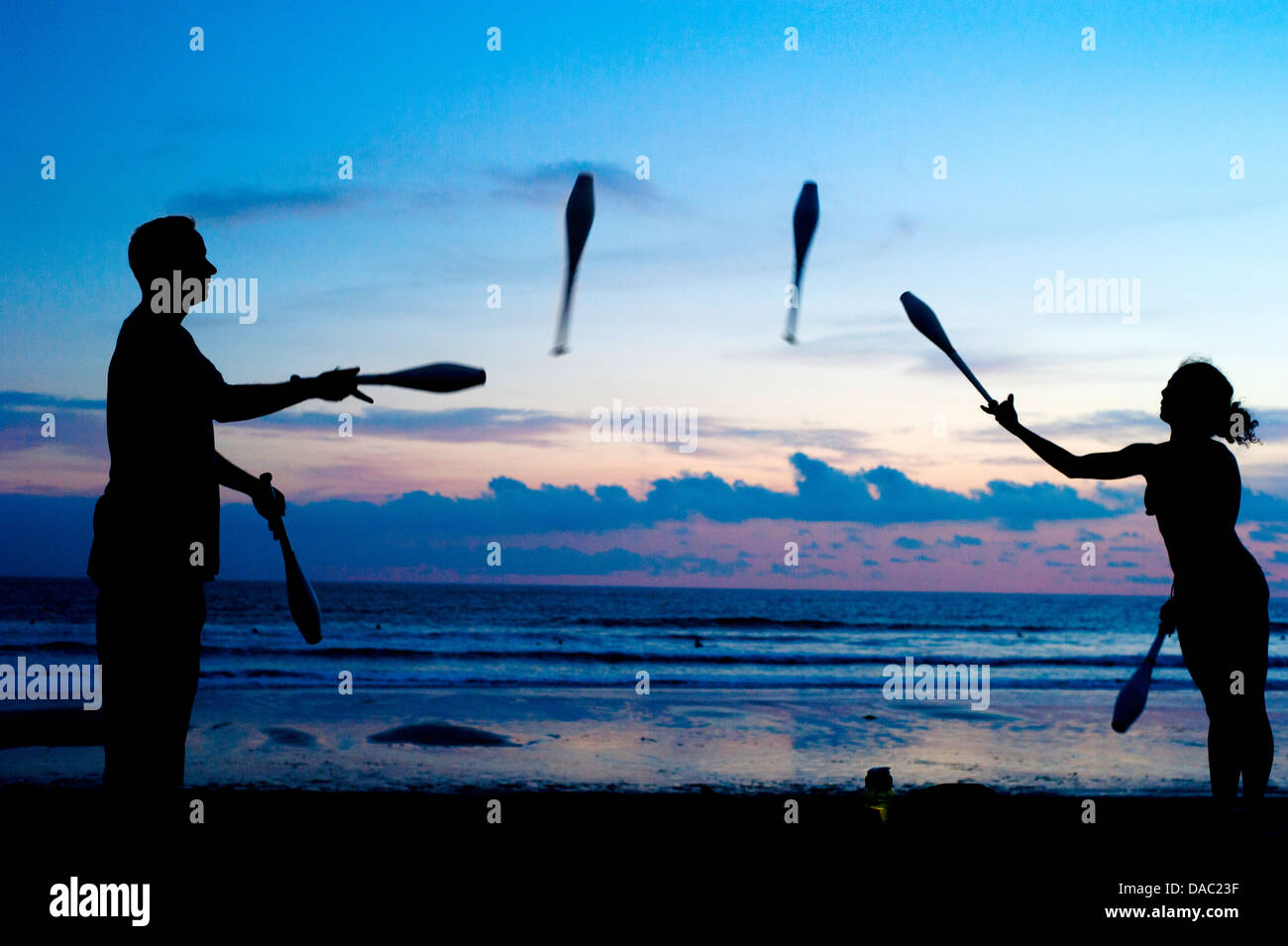 Mann und Frau jonglieren am Ocean Beach bei Sonnenuntergang. Bali, Indonesien Stockfoto