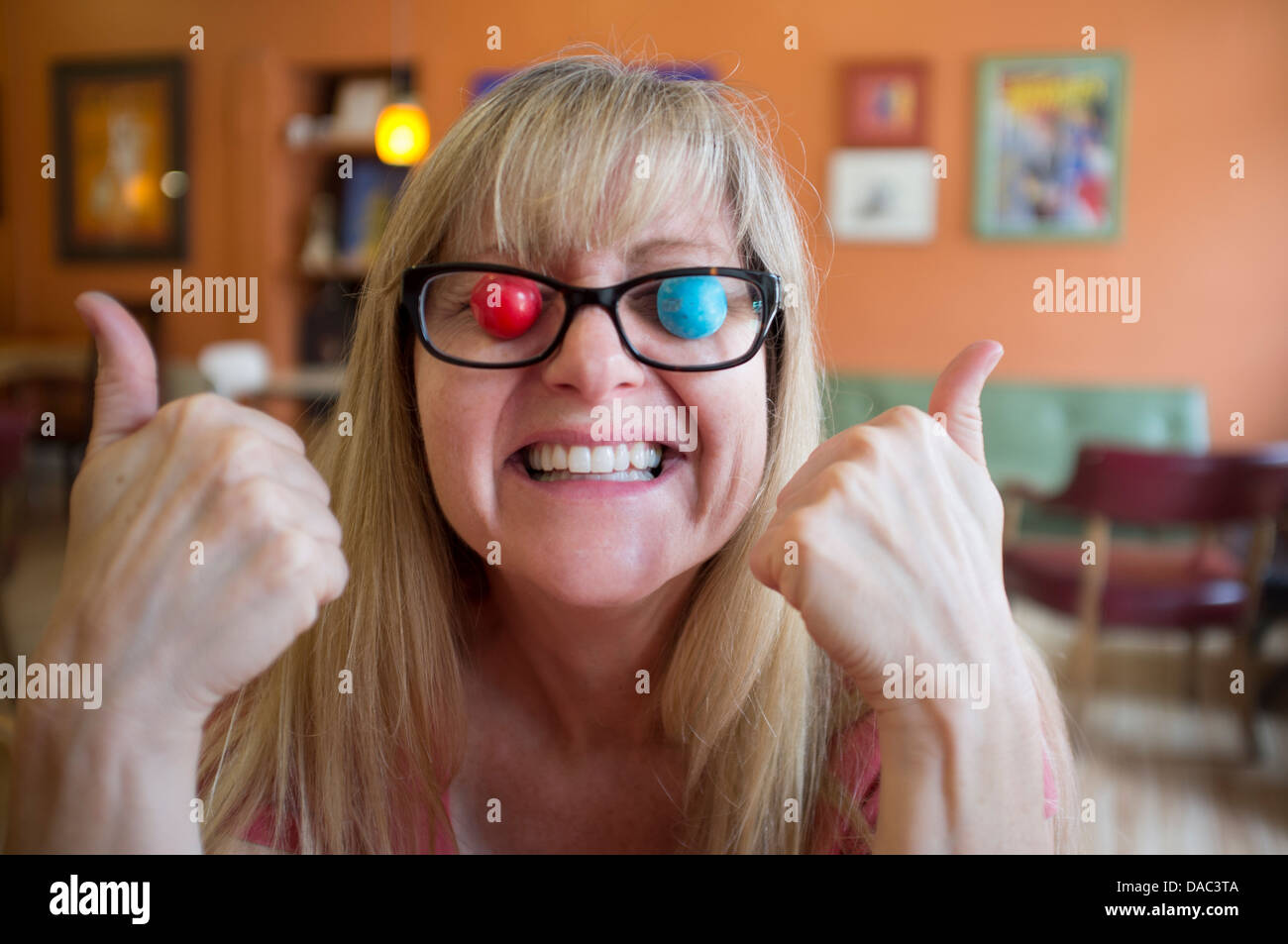 Frau mit Kaugummi Kugel Augen und Brille Daumen aufgeben. Stockfoto