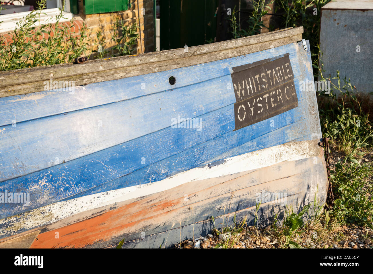 Boot mit Whitstable Oyster unterzeichnen, blaues und rotes altes Boot im Vordergrund Stockfoto